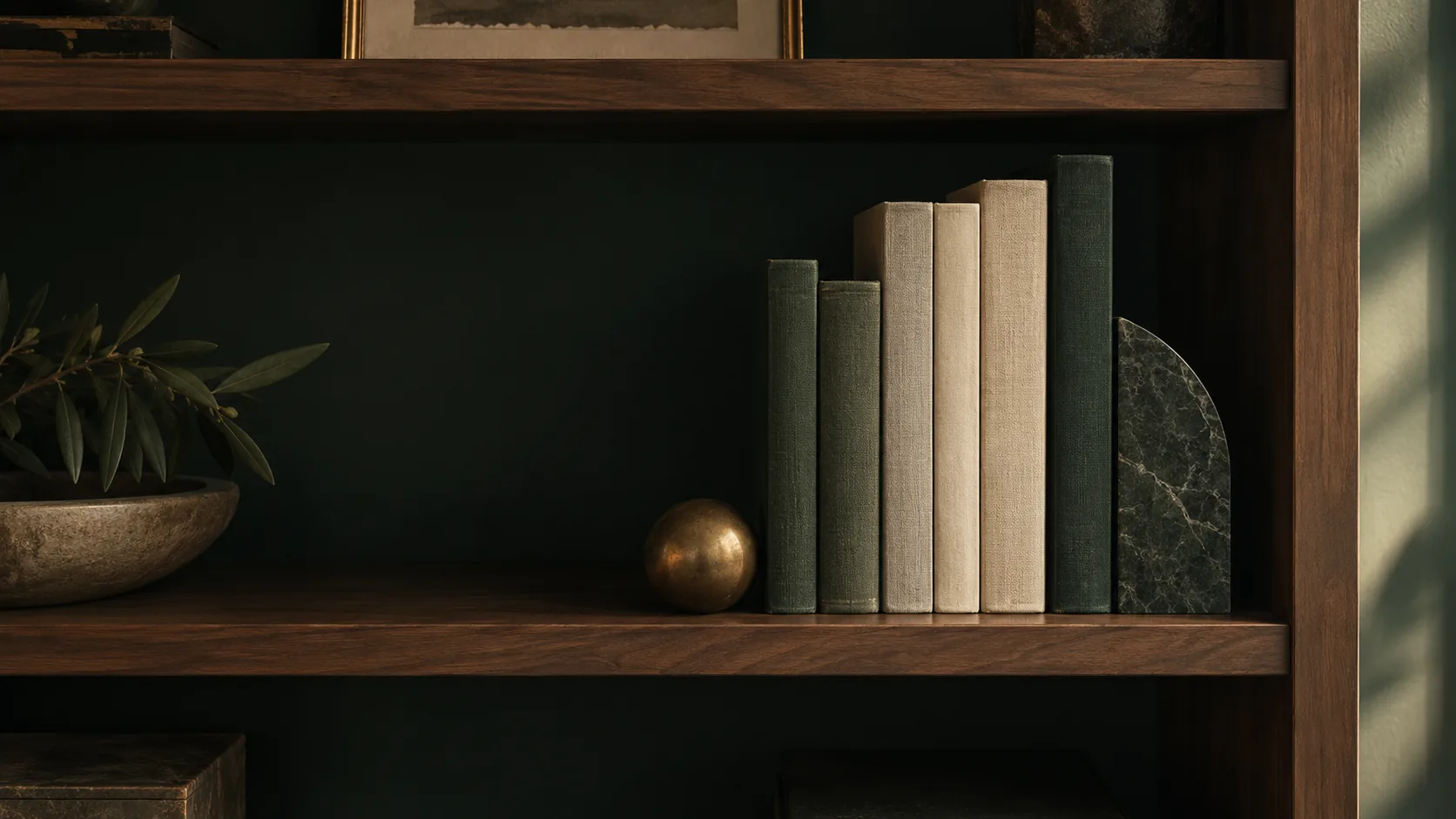 Cloth-bound books and a brass sphere on a walnut shelf.